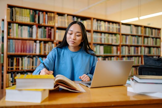 Young woman studying in a library with books and laptop, focusing on education.